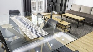 A modern living room with a glass dining table, black chairs, a sofa, and a TV. - Perfect destination in the historic center (Málaga)