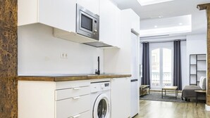 A modern kitchen with a built-in washing machine, a microwave, and a sink. - Perfect destination in the historic center (Málaga)