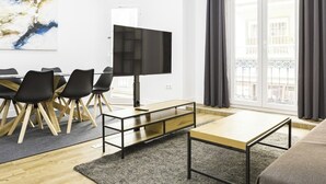A modern living room with a dining area, a flat-screen TV, and large windows with curtains. - Perfect destination in the historic center (Málaga)