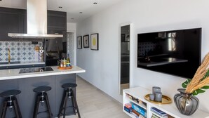 A modern kitchen with a central island, bar stools, a built-in oven, and a large window. - Charming Holiday Apartment in Nerja (Nerja)