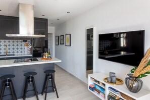 A modern kitchen with a central island, bar stools, a built-in oven, and a large window. - Charming Holiday Apartment in Nerja (Nerja)