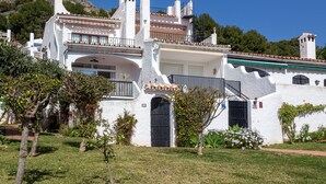 A white building with a balcony and a small garden area in front. - Charming Holiday Apartment in Nerja (Nerja)