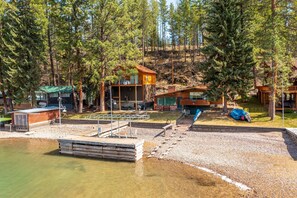 Un chalet au bord du lac, doté d’un quai et entouré d’arbres.
