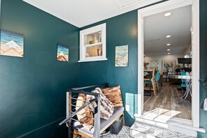 Ein Zimmer mit türkisfarbenen Wänden, einem Fenster, einer Bank mit Kissen und einem Essbereich mit Stühlen und einem Tisch.