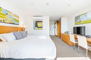 Een hotelkamer met een groot bed, een bureau met een televisie en kunst aan de muren.