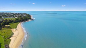 An aerial view of a coastal area with a beach, a pier, and a residential area. - Relaxed Esplanade Living near Pier & Marina (Urangan)