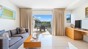 A modern living room with a sofa, coffee table, and TV stand. - Relaxed Esplanade Living near Pier & Marina (Urangan)