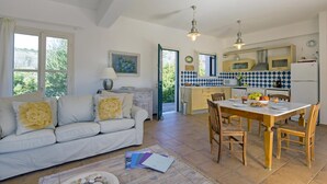 Ein gemütliches Wohnzimmer mit einer Couch, einem Esstisch mit Stühlen und einer Küchenzeile inklusive Kühlschrank und Schränken.