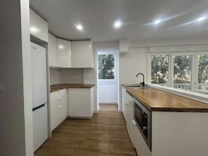 A modern kitchen with white cabinets, a wooden countertop, and a window with a view of trees. - Your getaway on the Fuengirola Promenade (Fuengirola)