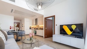 Un soggiorno moderno con un divano, un tavolino in vetro, una TV su un mobile bianco e un'area pranzo con tavolo e sedie.