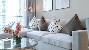 Un soggiorno moderno con un divano grigio, cuscini decorati, un tavolino in vetro e un vaso con fiori.