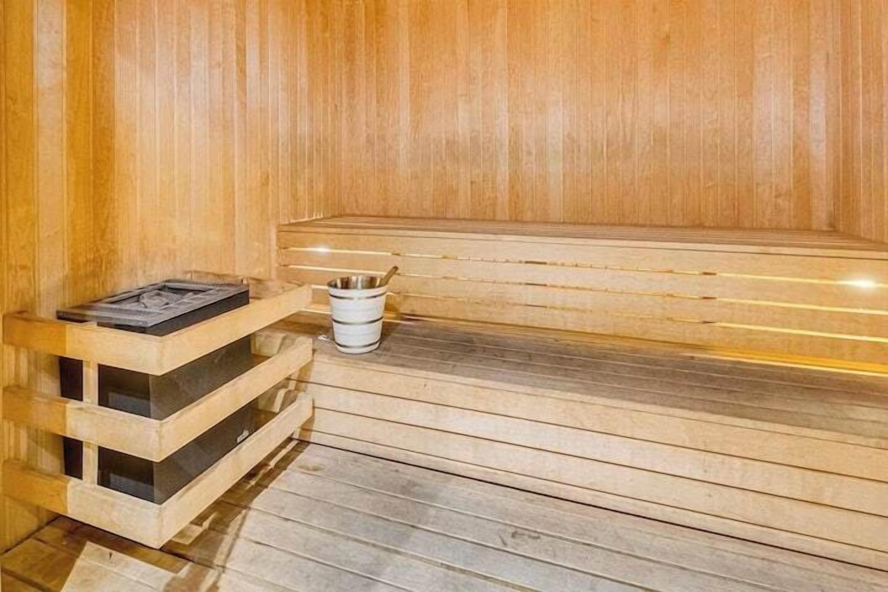Een sauna met houten banken en een klein tafeltje met een handdoek en een bak.