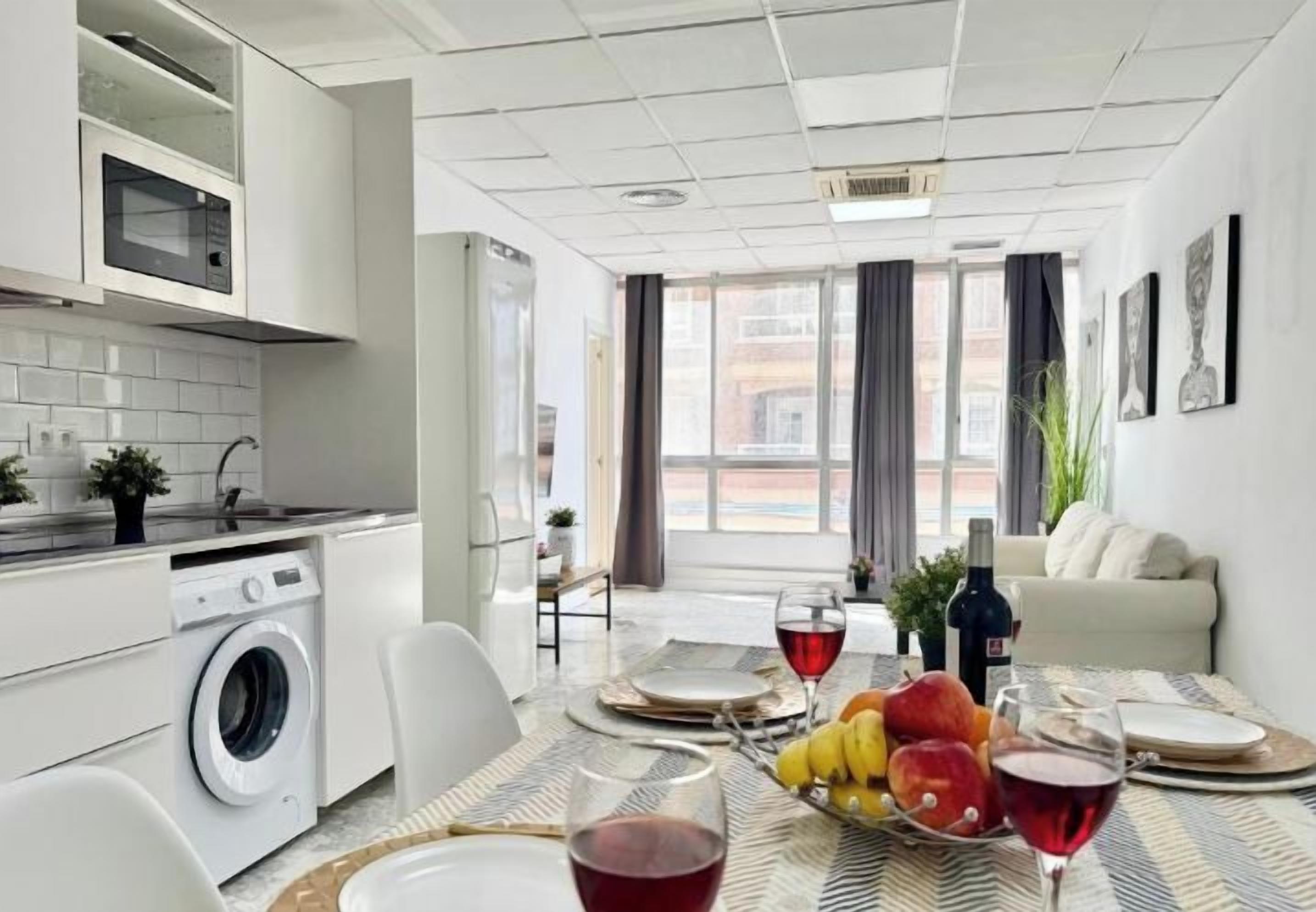 Una cucina moderna con lavatrice, tavolo da pranzo apparecchiato con piatti, bicchieri e frutta.