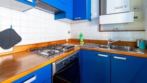 A kitchen with blue cabinets, a gas stove, a sink, and a microwave. - Welcome in Trastevere apartment (Roma)
