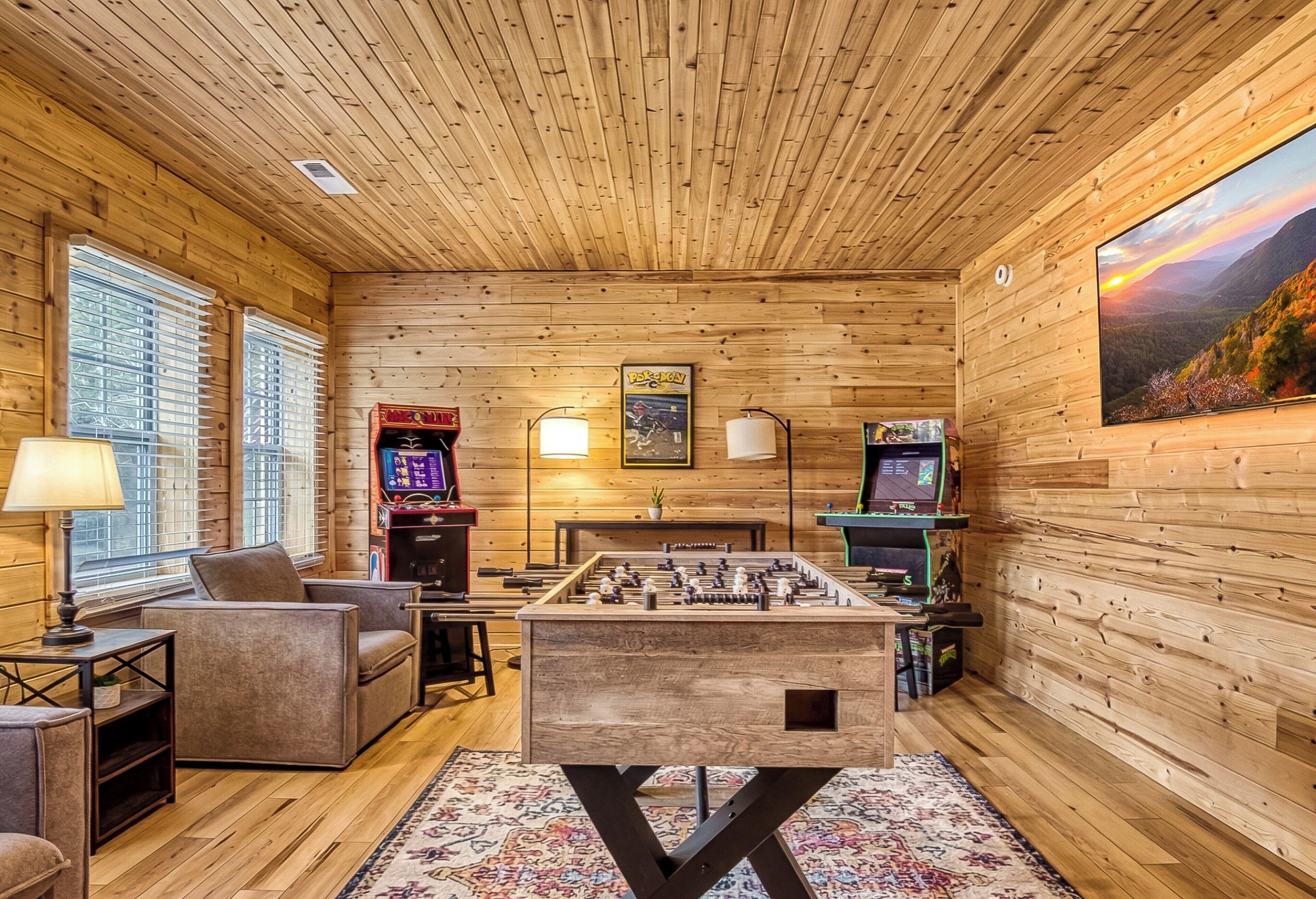 Ein gemütliches Zimmer mit Holzwänden, einem Tischkicker, einer Couch und einem Fernseher.