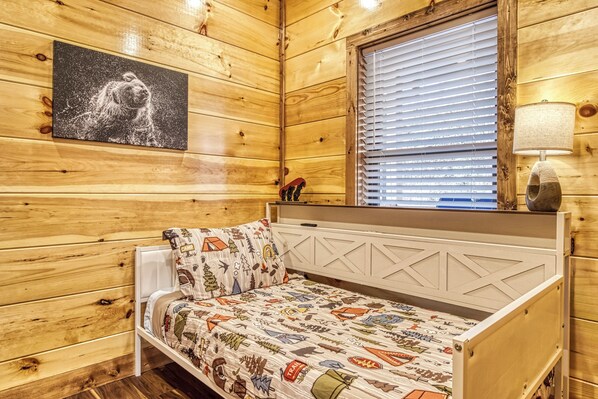 A wooden cabin room with a bed, a window with blinds, a lamp, and a painting on the wall. - Longview Lodge - Mountain Views, Hot Tub, Game Room (Gatlinburg)