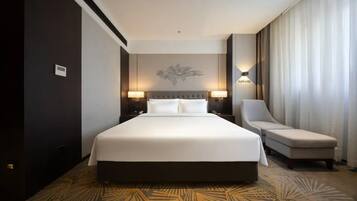 A hotel room with a large bed, two bedside lamps, a chair, and a large window with curtains.
