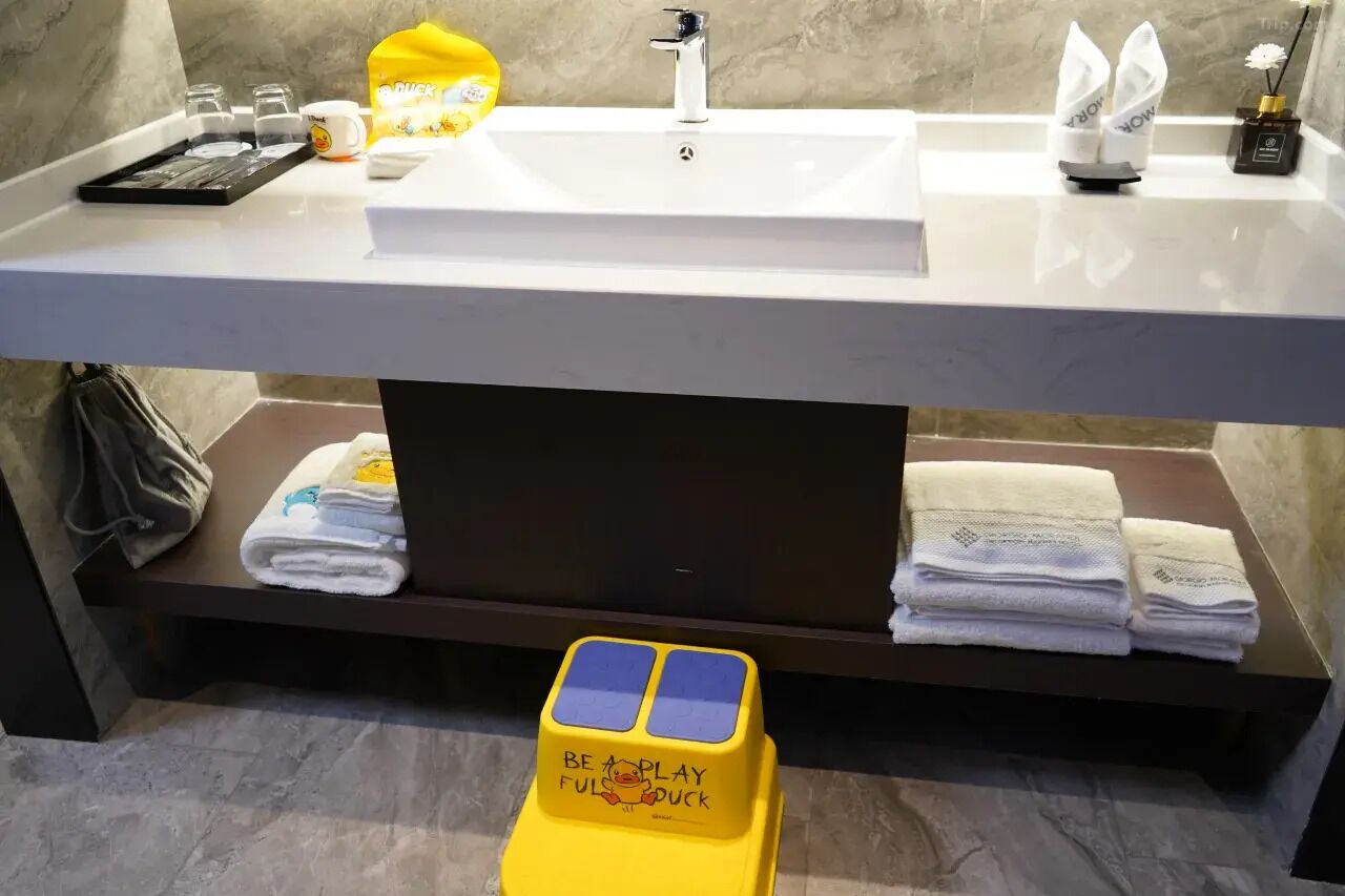 A bathroom with a white sink, a towel rack, and a yellow toy duck.
