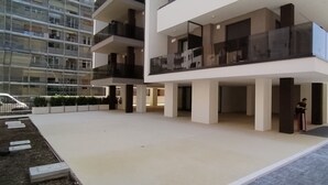Een modern gebouw met een ruime binnenplaats, meerdere balkons en een persoon in de buurt van de ingang.