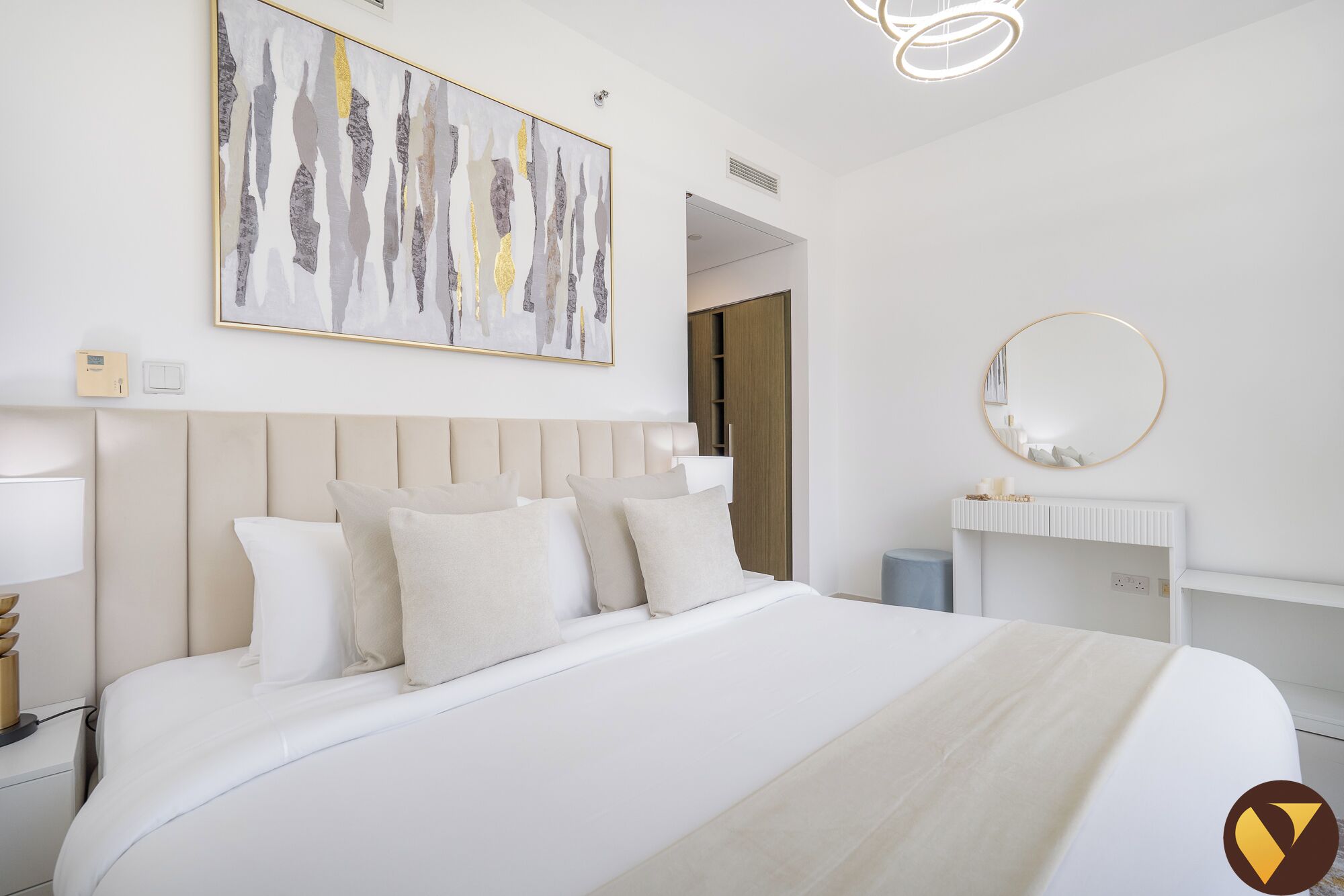 Une chambre moderne avec un grand lit, une table de chevet avec une lampe, un miroir fixé au mur et un tableau.