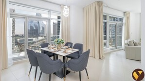 Een moderne eetruimte met een tafel voor vier personen, grote ramen met gordijnen en uitzicht op stadsgebouwen.
