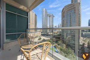 A balcony with wicker chairs and a glass table overlooking a cityscape with modern buildings. - Vogue | The Lofts near Burj Khalifa | Dubai Mall (Dubai)