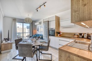 A modern kitchen with a dining area, wooden accents, and a view of the city. - Sofia`s Designer Apartment (St. Julian`s)