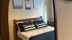 A bedroom with a bed, a bedside table, a lamp, and framed pictures on the wall. - Your refuge in Guarujá, just steps from the beach! BRA (Guarujá)