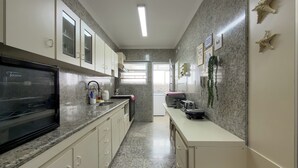 A modern kitchen with granite countertops, white cabinetry, and a black refrigerator. - Your refuge in Guarujá, just steps from the beach! BRA (Guarujá)