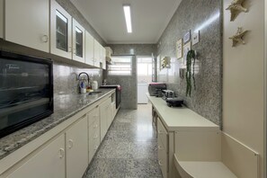 Eine moderne Küche mit Granit Arbeitsplatten, weißen Schränken und einem schwarzen Kühlschrank.
