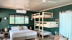 Ein Zimmer mit einem Bett, einem Etagenbett, Korbmöbeln und einem Deckenventilator.