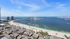 Eine Küstenstadt mit einem markanten Riesenrad, einem Strand und einem Yachthafen.