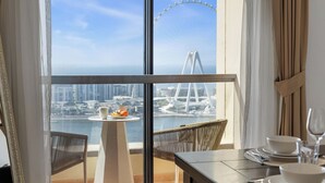 Ein Balkon mit Tisch für zwei Personen, mit Blick auf eine Stadtlandschaft und einer markanten Brücke.