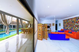 Un moderno salón con vista a la piscina, un sofá azul y un tapiz colorido.