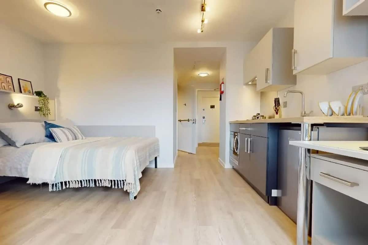 Une chambre moderne avec un lit, une table de chevet et une vue sur la cuisine adjacente.