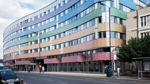 A multi-story building with a modern design, featuring a curved facade and a mix of glass and patterned panels. - Student Only Highbury (London)