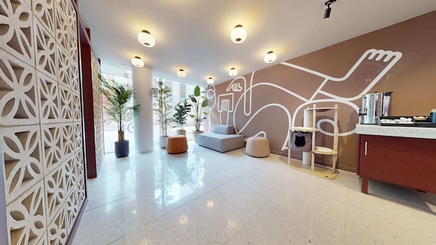 A modern lobby with a geometric wall design, a reception desk, and seating areas. - Student Only Highbury (London)