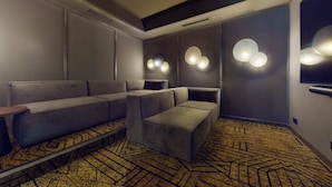 A modern cinema room with plush seating, wall-mounted lights, and a patterned carpet. - Student Only Highbury (London)