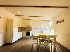 A kitchen with wooden cabinets, a stove, and a dining table with chairs. - Relax house, 5 minutes from the sea (Olbia)