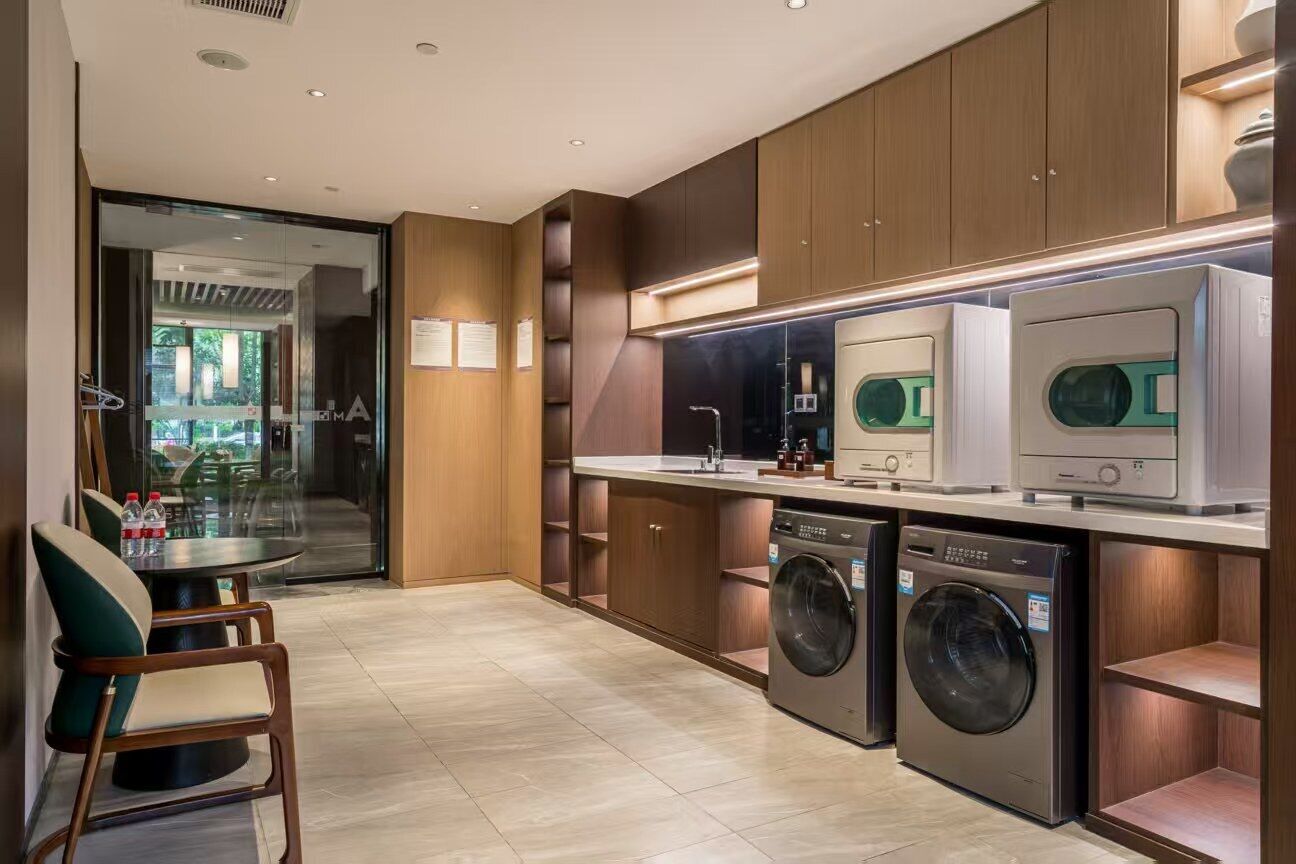 A modern kitchen with built-in appliances, a dining area with chairs, and a view through a glass door.