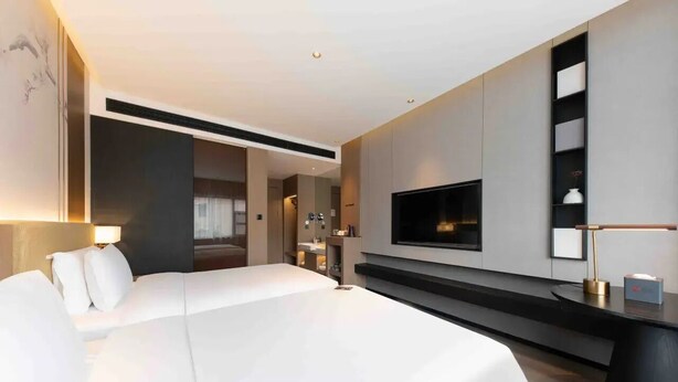A modern hotel room with a large bed, a flat-screen TV mounted on the wall, a bedside table, and a built-in shelf. - Giorgio Morandi Hotel - Xuyi Kejie Central Mall  (Huai'an)