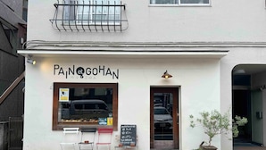 Un escaparate con un letrero que dice 'PANet GOHAN' y un pequeño espacio al aire libre con sillas.