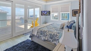 Une chambre avec un lit, une télévision et un balcon donnant sur l’océan.