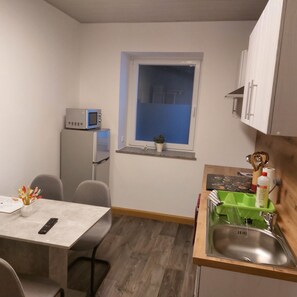 A compact kitchen with a refrigerator, microwave, sink, and a small window. - "Am Schloss Hubertusburg" Vacation Rental, Centrally Located in Wermsdorf (Wermsdorf)