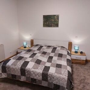 A bedroom with a bed, two bedside tables, a nightstand, a lamp, and a painting on the wall. - "Am Schloss Hubertusburg" Vacation Rental, Centrally Located in Wermsdorf (Wermsdorf)