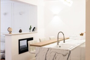 Un baño moderno con lavamanos de mármol, tocador de madera y un espejo grande.