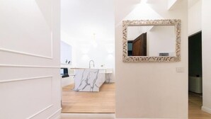 En hall med ett handfat i marmor och en dekorativ spegel.