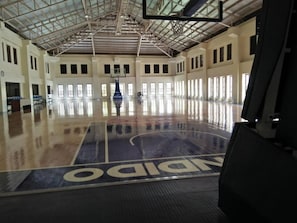 Un terrain de basket-ball intérieur orné du logo Spalding, doté de grandes fenêtres et d’un plafond haut.
