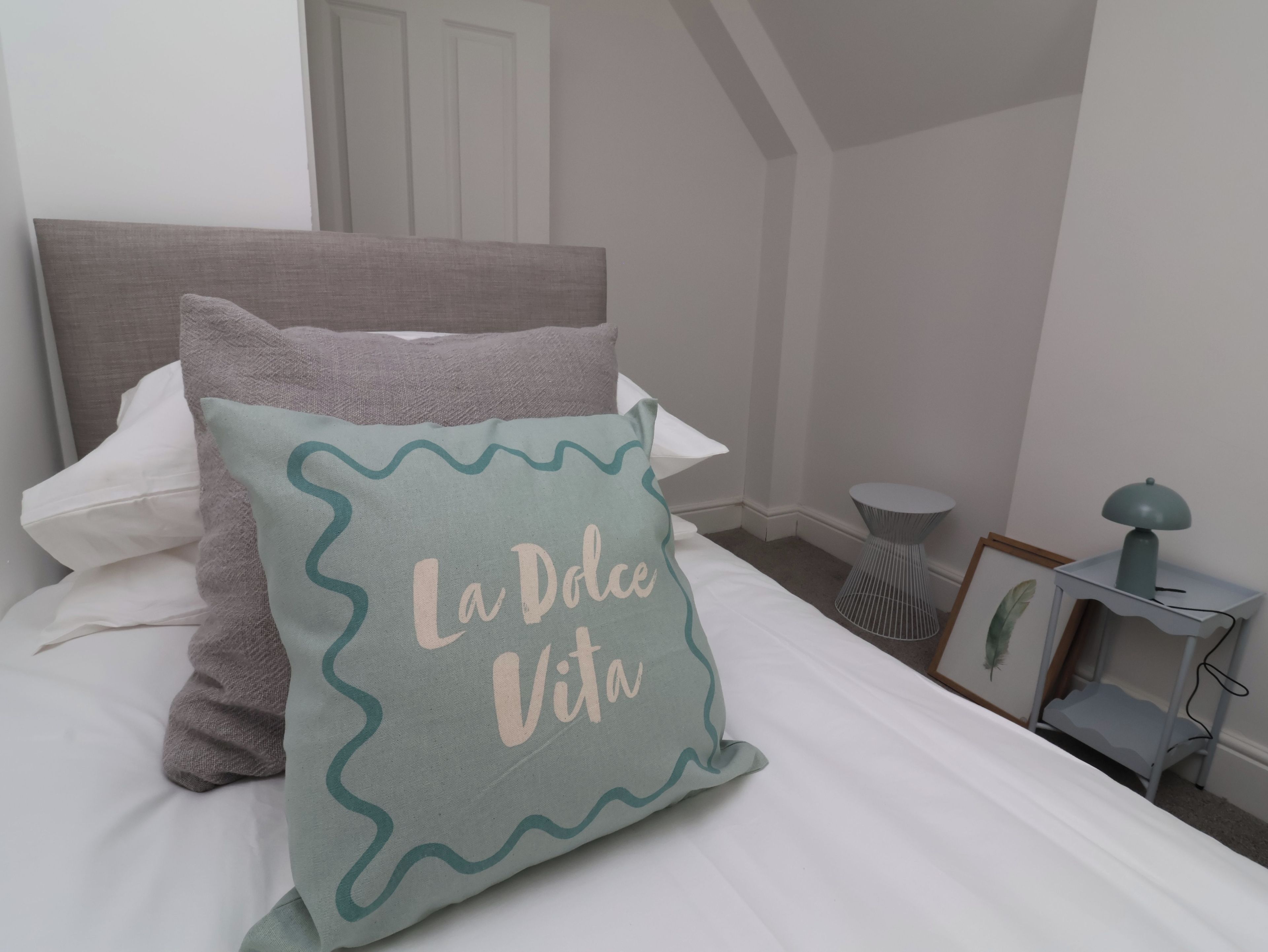 Cama bem arrumada com travesseiro e bordado decorativo.