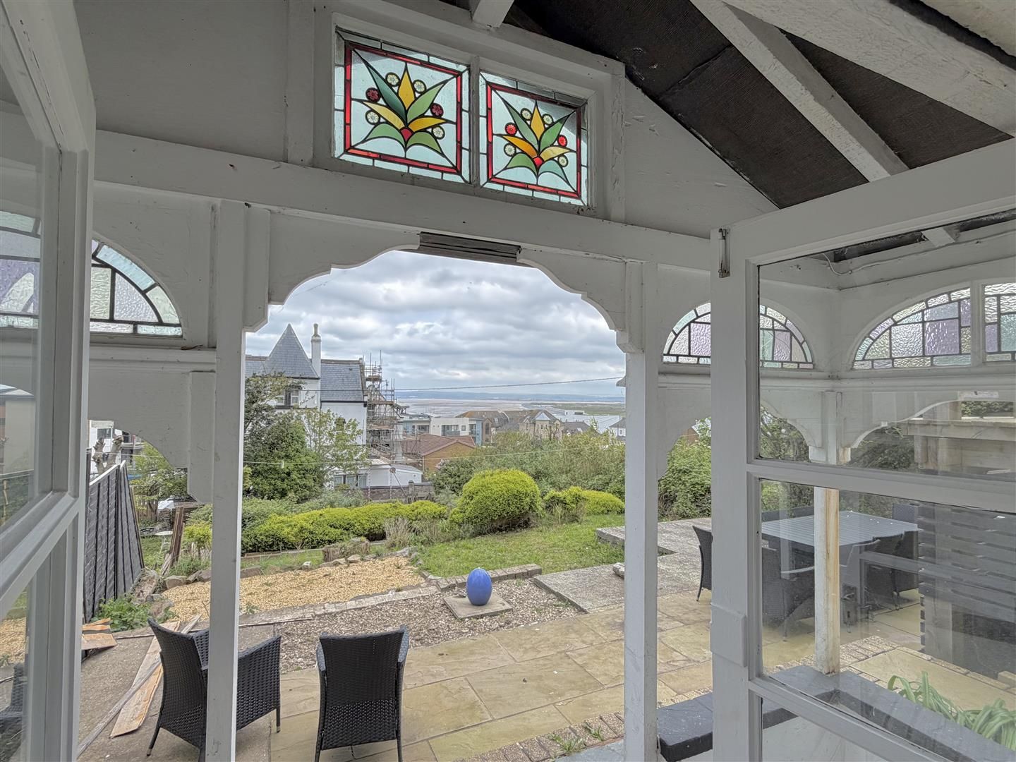A conservatory with a view of a garden and a distant building.